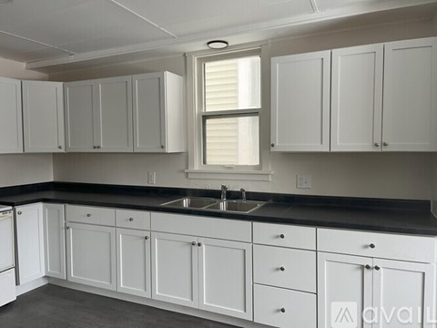 A kitchen with white cabinets and a black countertop.