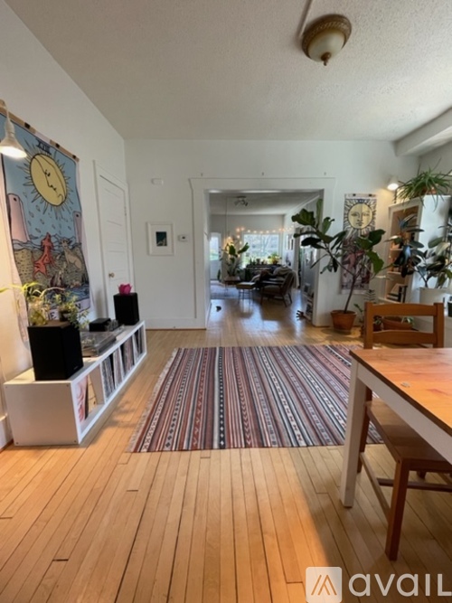 A living room with a wooden floor and a rug in the middle.