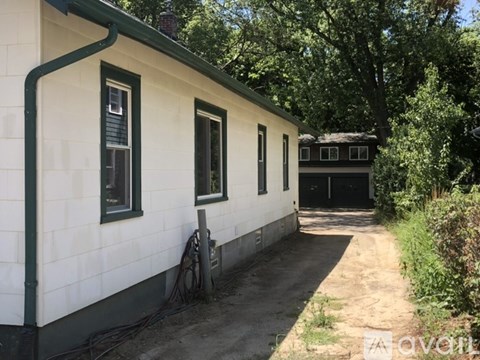 A white building with a green roof and a dirt path leading to it.