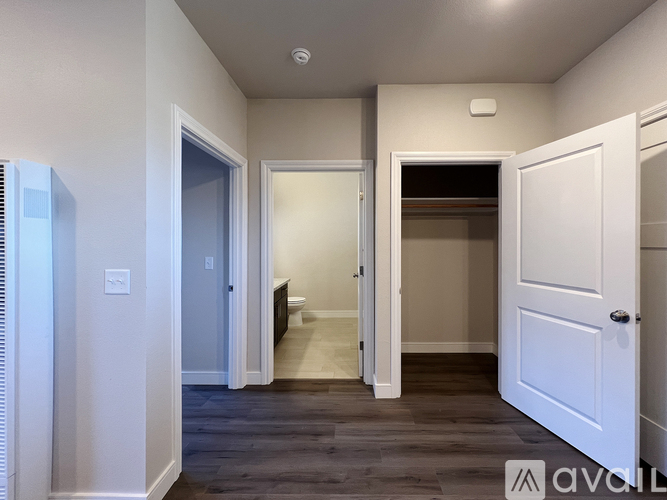 A hallway with a white door on the right and a window on the left.