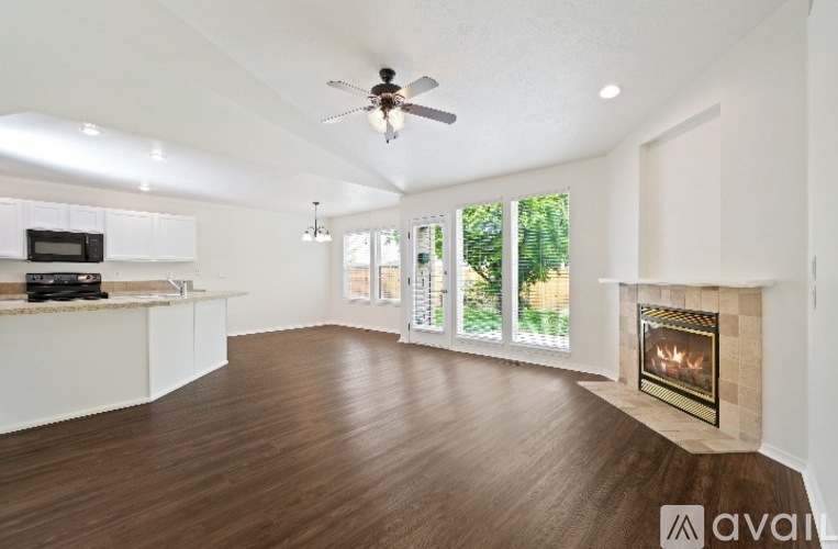 A spacious living room with a fireplace and a ceiling fan.