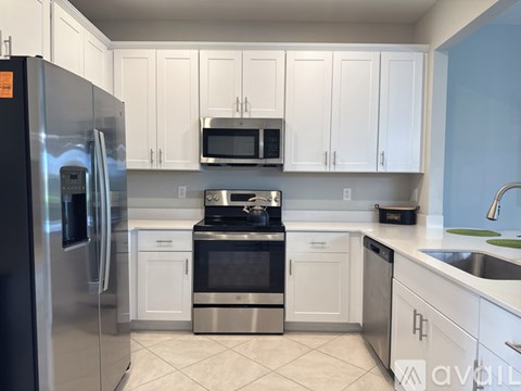 A kitchen with white cabinets and a stainless steel refrigerator.