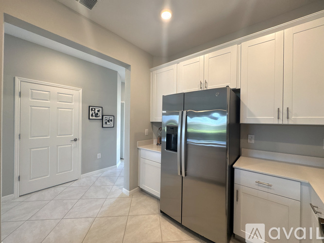 A kitchen with a stainless steel refrigerator and white cabinets.