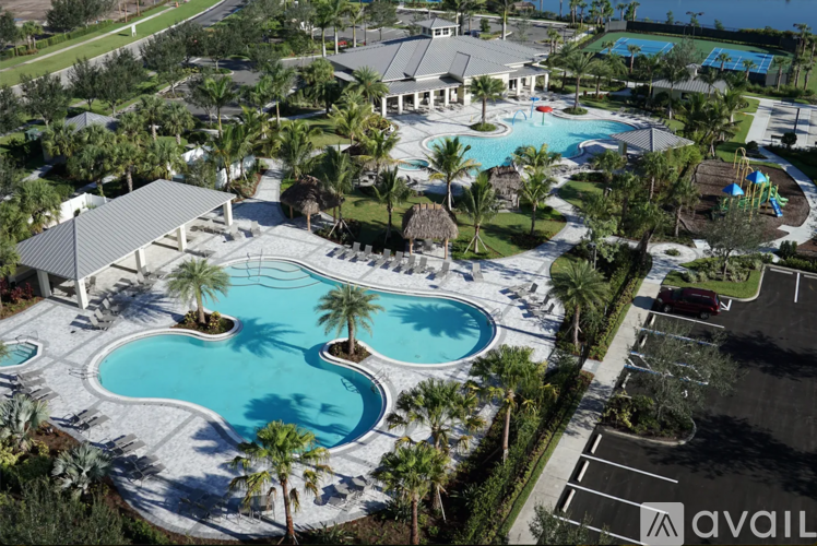A large swimming pool surrounded by palm trees and a pavilion.