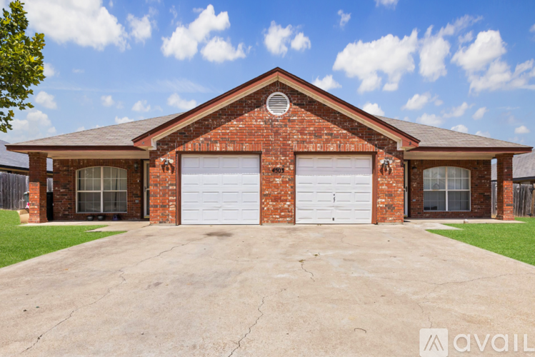 A red brick house with two white garage doors.