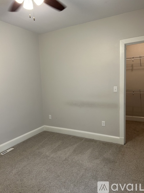A room with a carpeted floor and a ceiling fan.