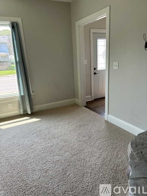 A carpeted room with a doorway leading to another room.