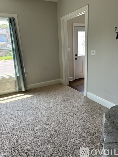 A carpeted room with a doorway leading to another room.