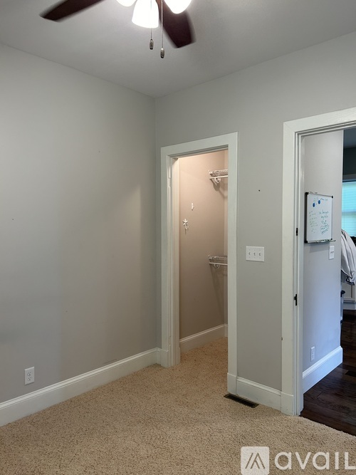 A room with a carpeted floor and a ceiling fan.