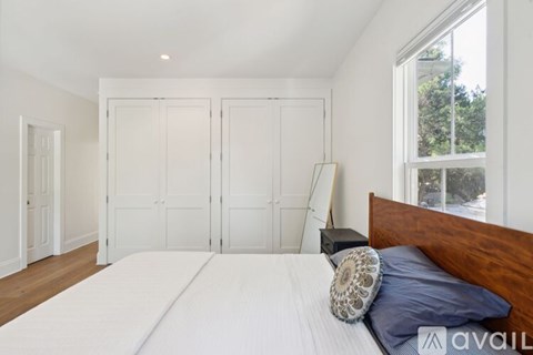 A bedroom with a large bed and a window overlooking a tree.
