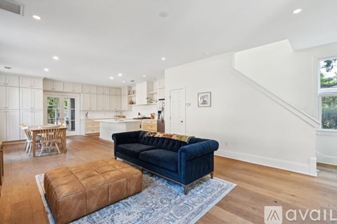 A living room with a blue couch and a brown ottoman.