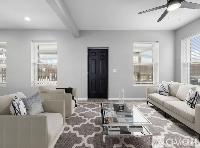 A modern living room with a black door, two sofas, and a glass coffee table.