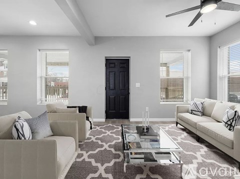 A modern living room with a black door, two sofas, and a glass coffee table.