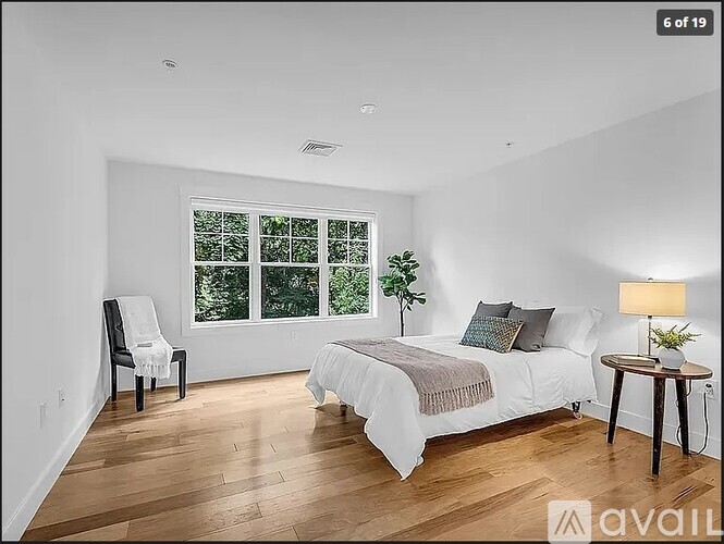 A bedroom with a bed, chair, and window.