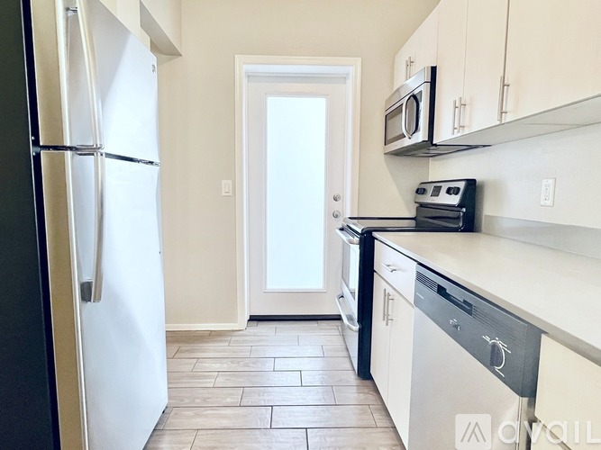 A kitchen with a black fridge and white cabinets.