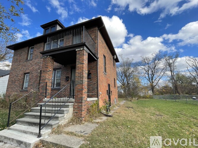A red brick house with a balcony and a black railing.