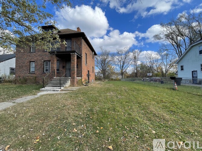 A house with a brown brick exterior and a white house in the background.
