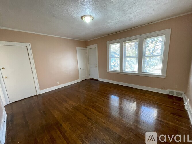 A room with wooden floors and a window with a view of trees outside.