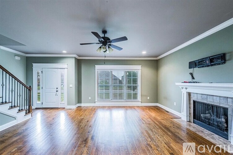 A spacious living room with a fireplace and a ceiling fan.