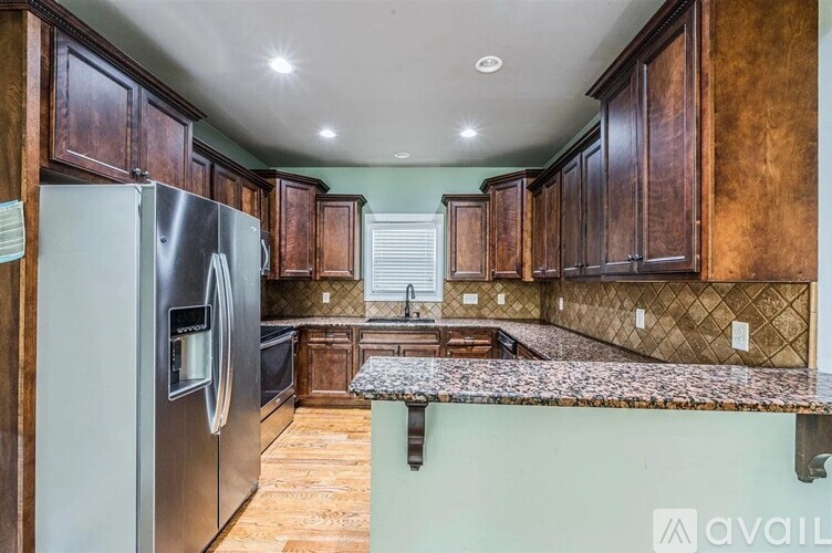 A kitchen with wooden cabinets and a stainless steel refrigerator.