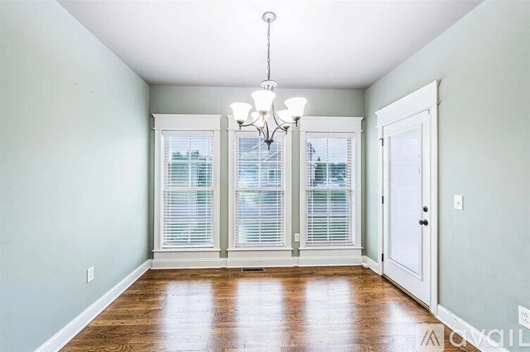 A room with a chandelier, a door, and a window with blinds.