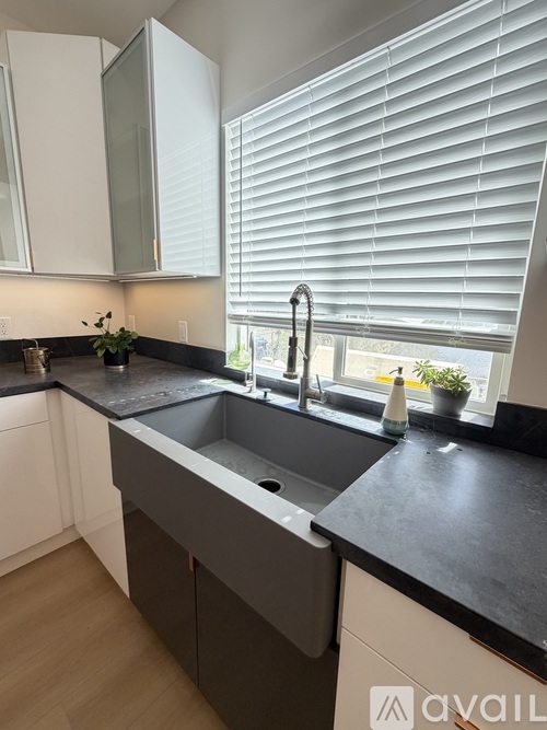 A kitchen with a black countertop and a grey sink.