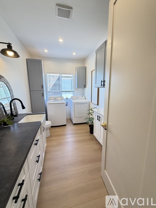A kitchen with white appliances and a black countertop.