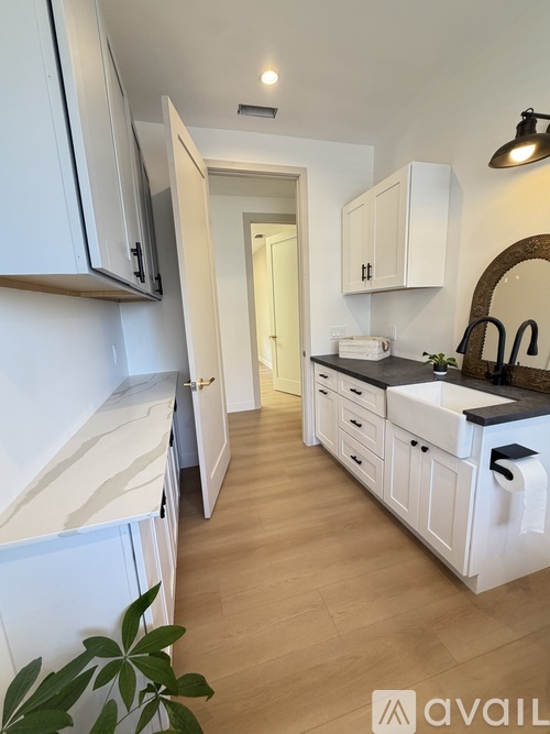 A kitchen with white cabinets and a wooden floor.