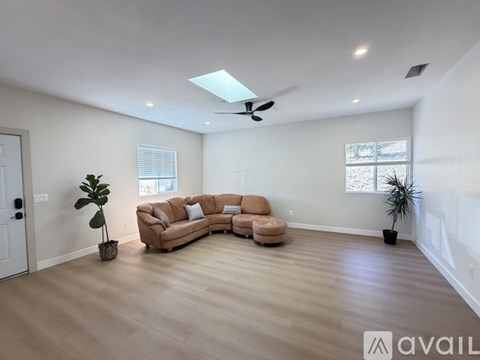 A living room with a tan couch and a ceiling fan.
