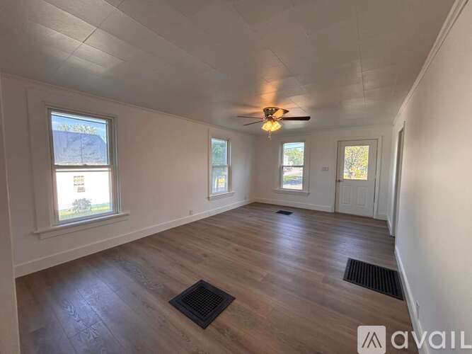 A room with a ceiling fan and wooden flooring.