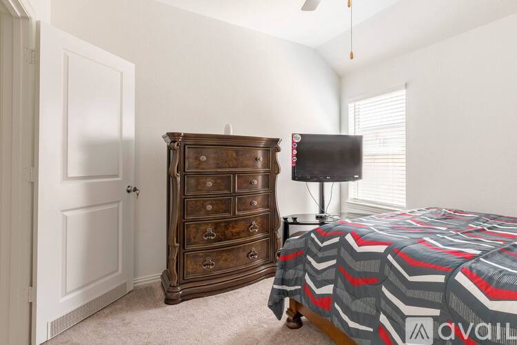 A bedroom with a bed, a dresser, and a window.