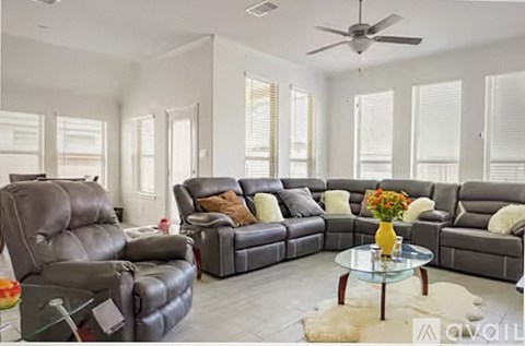 A living room with a grey sofa set and a glass coffee table.