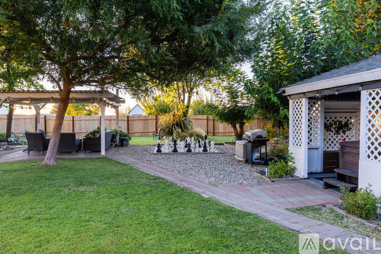 A backyard with a gazebo, a fire pit, and a gravel path.