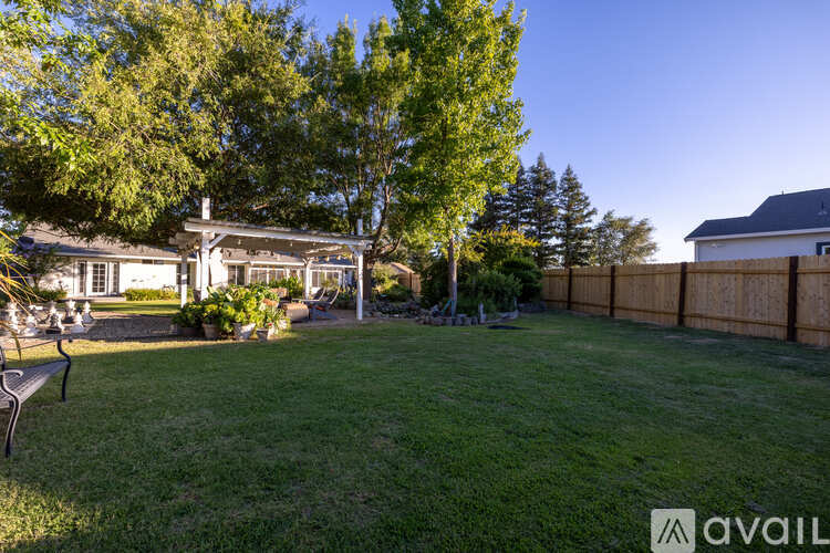 A backyard with a lawn, trees, and a fence.