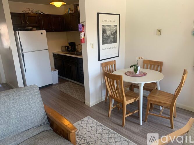 A kitchen with a refrigerator, a dining table with chairs, and a couch.
