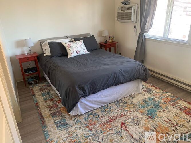 A bedroom with a bed, nightstand, and window.