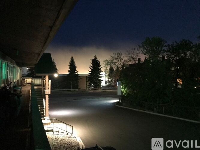 A dark road with street lights and trees on the side.