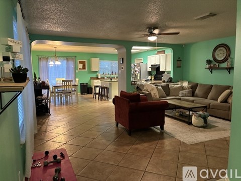 A living room with a red couch and a dining area with a table and chairs.