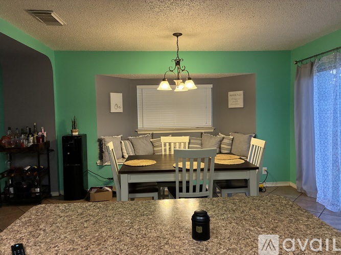 A dining room with a table set for four and a chandelier hanging from the ceiling.