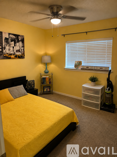 A bedroom with a yellow bed and a ceiling fan.