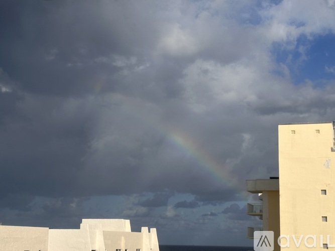 A rainbow appears in the sky above a white building.