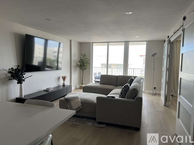 A modern living room with a grey sofa and a television on the wall.