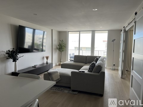 A modern living room with a grey sofa and a television on the wall.