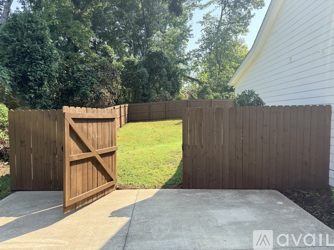 A wooden gate is open to a grassy area.