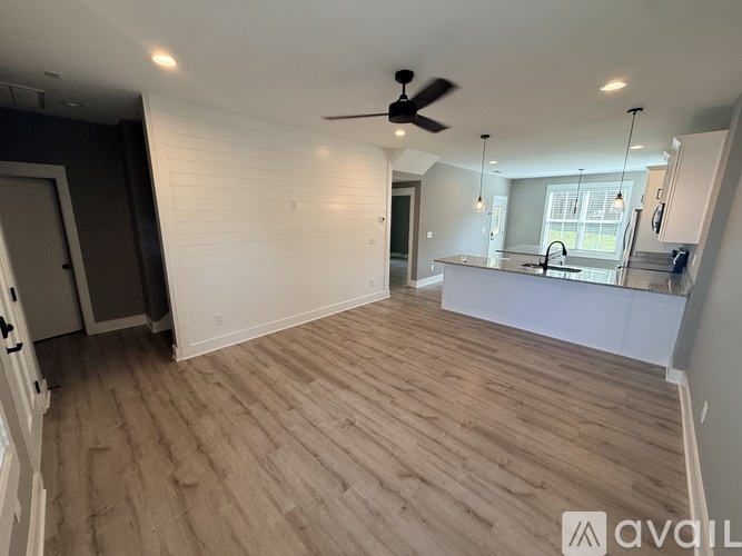 A spacious room with wooden flooring and a ceiling fan.