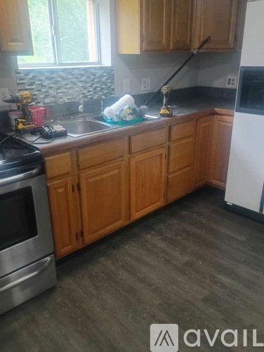A kitchen with wooden cabinets and a black fridge.
