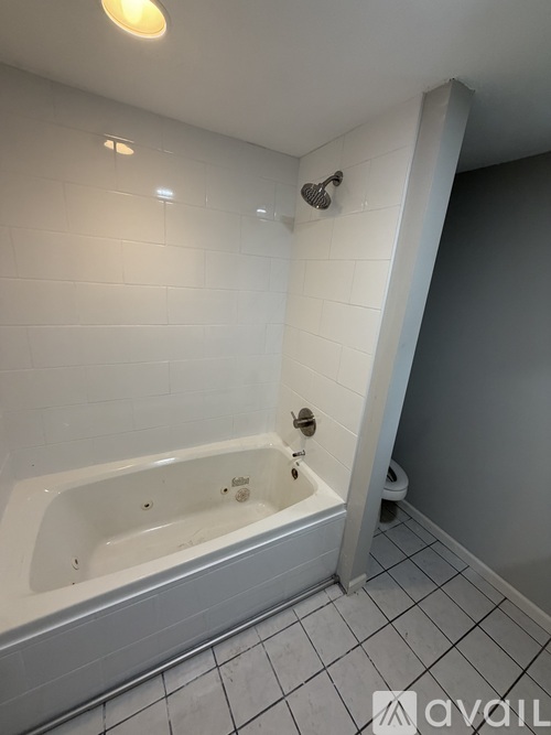 A white bathtub in a bathroom with grey walls.