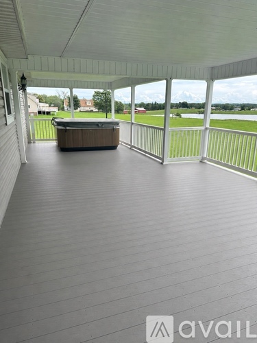 A hot tub is on a covered deck with a view of the yard.