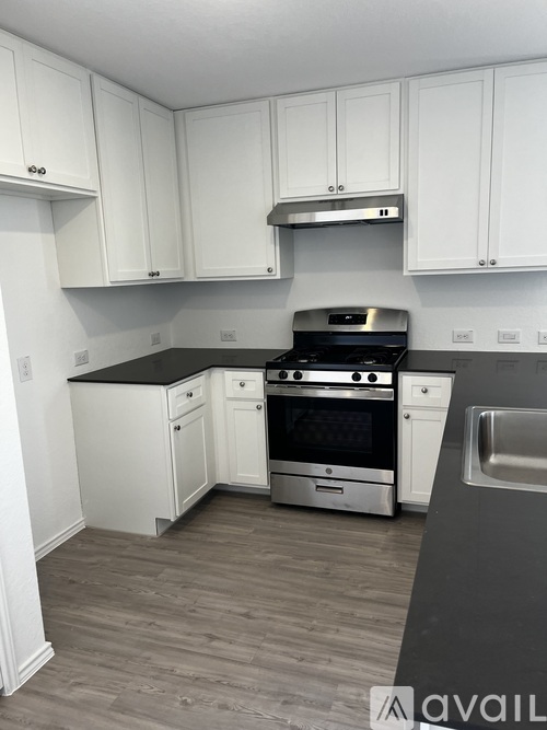 A kitchen with white cabinets and a black countertop.