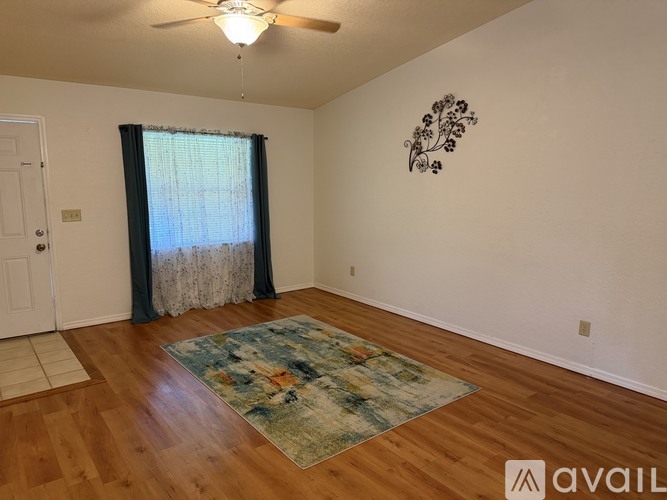 A room with a ceiling fan and a wall art of a tree.